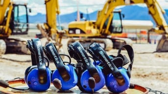 Four Sonetics wireless headsets on the ground in front of construction equipment